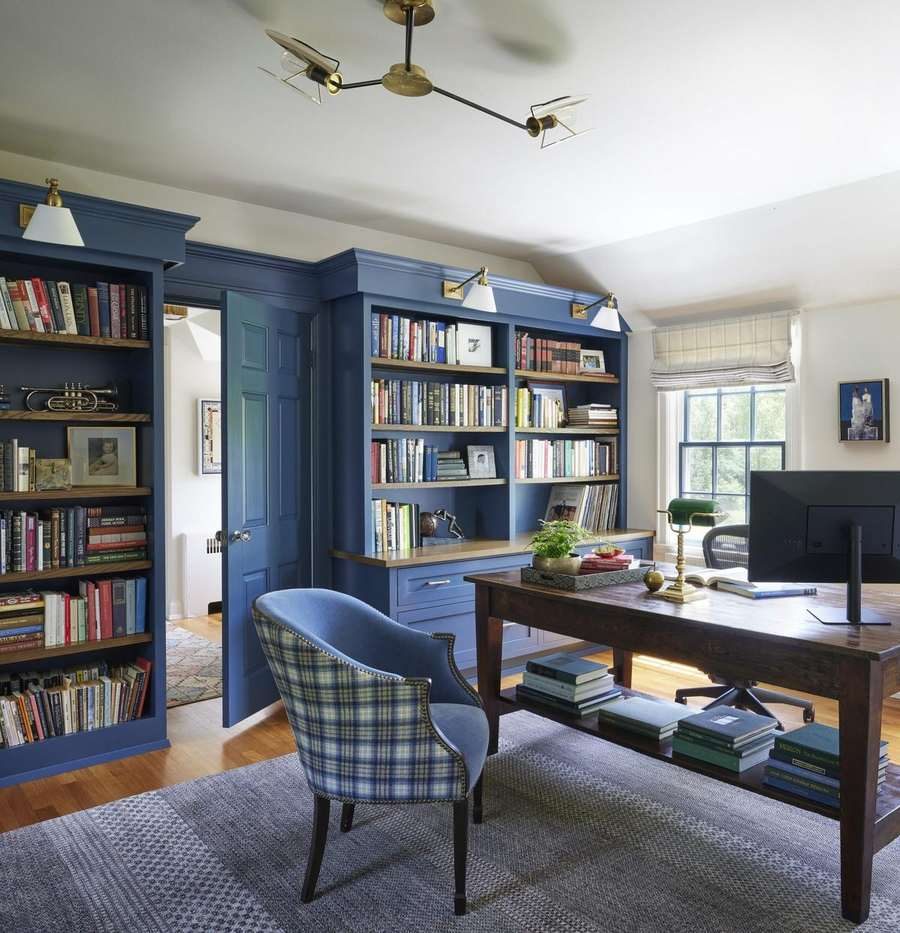 Curated Home library and home office with blue built-in bookcases, a plaid upholstered chair, and an antique wood desk, designed by Kimberly Knight of Twig and Trove Interiors